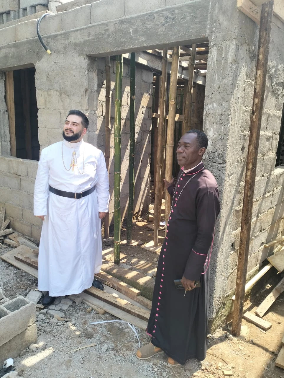 Missionaries beside a building under construction.